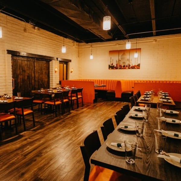 The Tap N Tikka dining room features orange booths, dark wood tables, and a Taj Mahal painting.