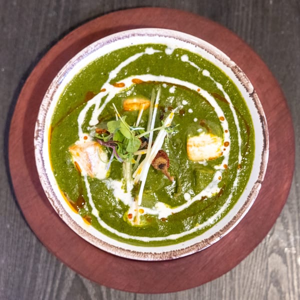 Overhead view of Tap N Tikka's Palak Paneer, a vibrant green Indian dish with paneer and cream swirls.